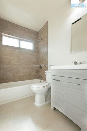 Los Angeles apartment for rent - A white toilet sits in a bathroom with a brown tiled wall and a white sink.