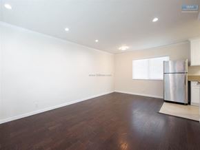 Los Angeles apartment for rent - A spacious room with wooden flooring and a stainless steel refrigerator.