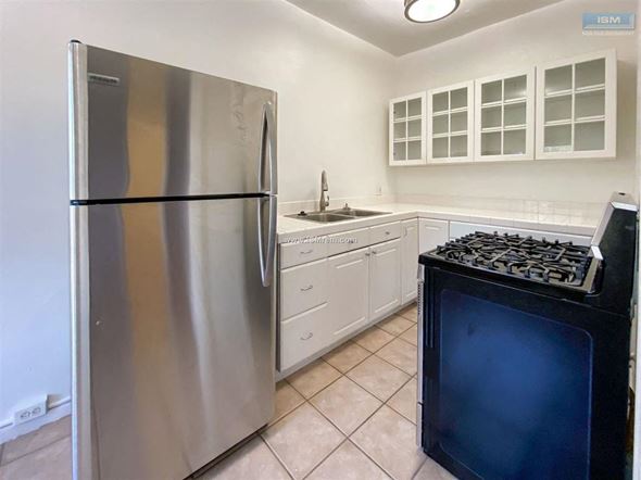 Los Angeles apartment for rent - A kitchen with a stainless steel refrigerator, white cabinets, and a black stove top.