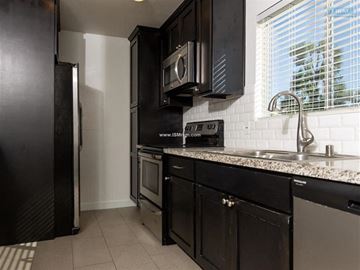 Los Angeles apartment for rent - A kitchen with black cabinets and a white tiled backsplash.