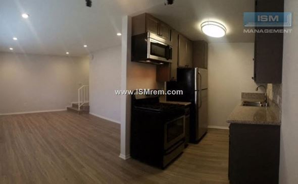 Sherman Oaks apartment for rent - A kitchen with a black refrigerator and wooden floors.
