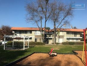 Stockton apartment for rent - A playground with a swing set and a building in the background.