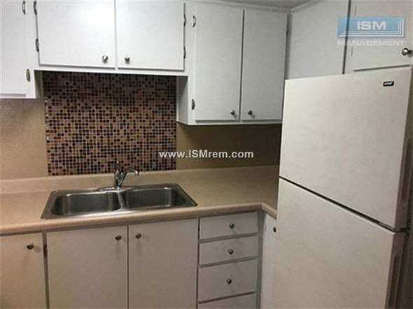 Stockton apartment for rent - A kitchen with white cabinets and a white fridge.