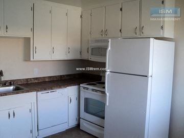 Turlock apartment for rent - A white refrigerator stands in a kitchen with white cabinets.