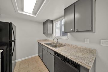 Redding apartment for rent - A kitchen with a black refrigerator and a granite countertop.