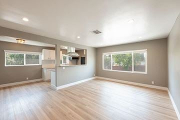 Los Angeles apartment for rent - A spacious room with wooden floors and a kitchen area in the background.