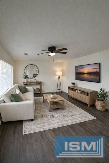 Carson City apartment for rent - A living room with a white couch, a wooden coffee table, a mirror, a ceiling fan, and a painting on the wall.