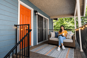 San Francisco apartment for rent - A woman is sitting on a couch on a porch with a book in her hands.