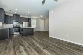 Bakersfield apartment for rent - a kitchen and living room with wooden floors and black cabinets