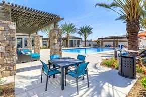Bakersfield apartment for rent - a patio with a table and chairs next to a swimming pool