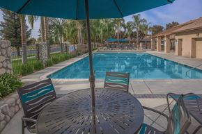 Bakersfield apartment for rent - a swimming pool with a table and chairs under an umbrella