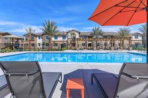 Bakersfield apartment for rent - a swimming pool with tables and chairs next to a resort style pool