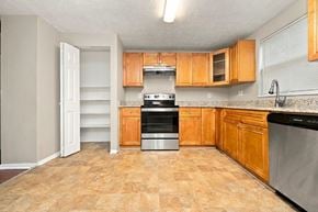 Lithonia house for rent - A kitchen with wooden cabinets and a black stove top oven.