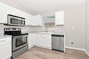 Atlantic Beach house for rent - A kitchen with white cabinets and a black stove top oven.