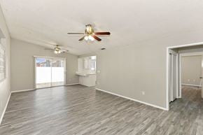 Hemet house for rent - A spacious room with a ceiling fan and sliding glass doors.