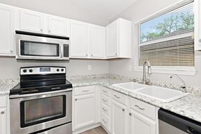 Atlantic Beach house for rent - A kitchen with white cabinets and a black stove top oven.