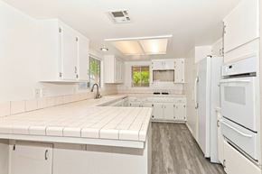 Hemet house for rent - A white kitchen with a refrigerator on the right.