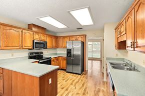Jacksonville house for rent - A kitchen with wooden cabinets and a black refrigerator.
