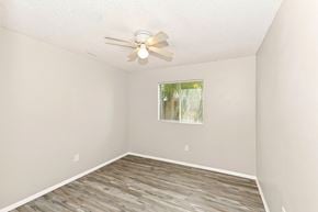 Hemet house for rent - A room with a ceiling fan and a window with a view of trees.