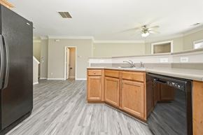 Fairburn house for rent - A kitchen with a black fridge and wooden cabinets.