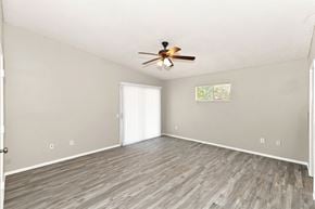 Hemet house for rent - A room with a ceiling fan and light, hardwood floors, and a window with blinds.