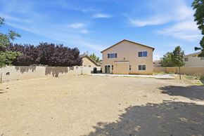 Lancaster house for rent - A large, empty lot with a two-story building in the background.