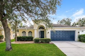 Brooksville house for rent - A house with a blue garage door and a tree in front.