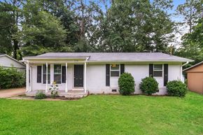 Newnan house for rent - A white house with a porch and green bushes in front.