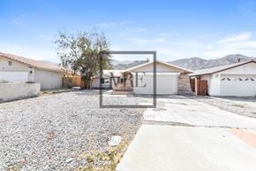 La Quinta house for rent - A gravel driveway leads to a white house with a brown roof.