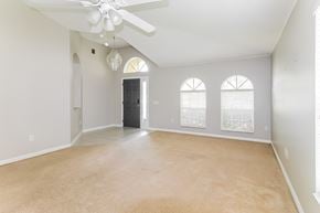Brooksville house for rent - A spacious room with a ceiling fan and three windows.