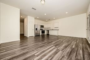 Mcdonough house for rent - A spacious room with wooden flooring and a kitchen area in the background.