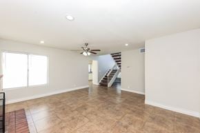 Moreno Valley house for rent - A spacious room with a ceiling fan and a staircase in the background.