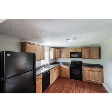 Conley house for rent - a kitchen with wooden cabinets and a black refrigerator