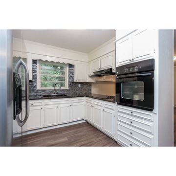 College Park house for rent - a kitchen with white cabinets and black appliances