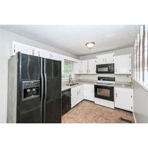 Hiram house for rent - A kitchen with black appliances and white cabinets.