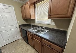 Adairsville house for rent - A kitchen with brown cabinets and a black countertop.