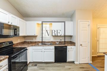 Hiram house for rent - A kitchen with white cabinets and black appliances.