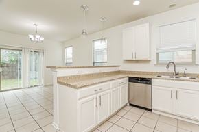 San Antonio house for rent - A kitchen with white cabinets and a granite countertop.