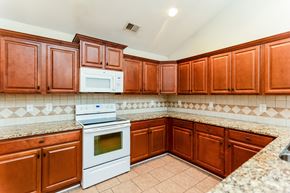 Cartersville house for rent - A kitchen with brown cabinets and a white stove top oven.
