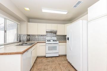 Moreno Valley house for rent - A white kitchen with a refrigerator, sink, and stove.