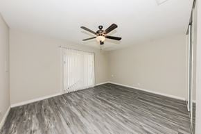 Indio house for rent - A room with a ceiling fan and wooden flooring.