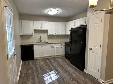 Hiram house for rent - a kitchen with white cabinets and a black refrigerator