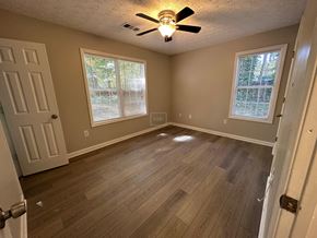 Hiram house for rent - an empty living room with wood floors and a ceiling fan