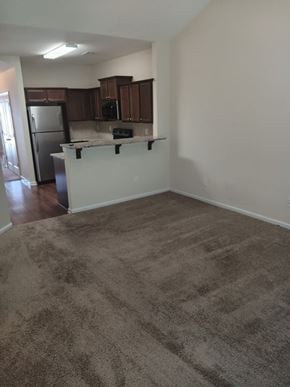 Woodstock house for rent - an empty living room with a kitchen and a carpeted floor