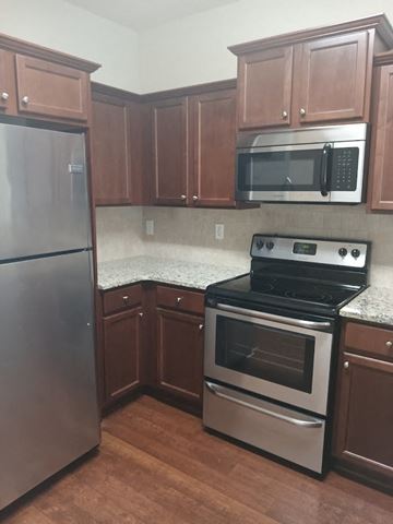 Woodstock house for rent - a kitchen with stainless steel appliances and wooden cabinets