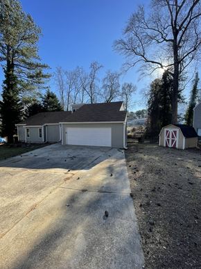 Douglasville house for rent - A house with a garage and a barn-like structure in front.
