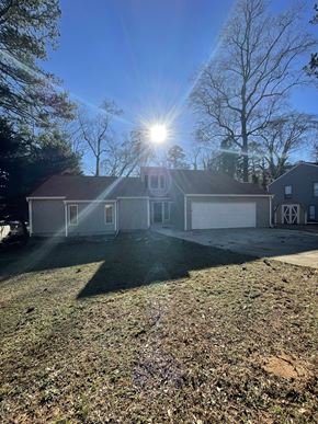 Douglasville house for rent - A house with a large front yard and a tree in the background.