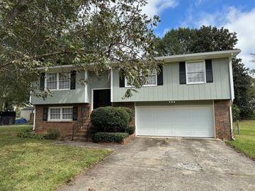 Riverdale house for rent - a green and brick house with a white garage door