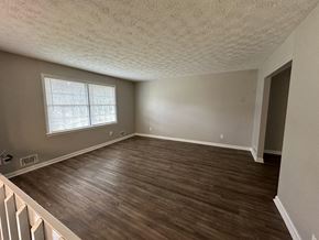 Riverdale house for rent - an empty living room with wooden floors and a window