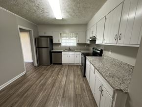 Riverdale house for rent - an empty kitchen with white cabinets and granite counter tops